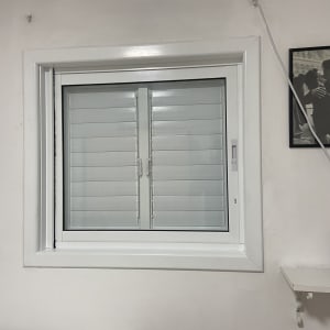 חלון אלומיניום עם תריסים סגורים על קיר לבן