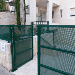 שערים ירוקים עם שלטים על קיר אבן