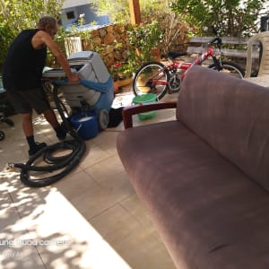 אדם מנקה ספה עם מכונת ניקוי ושואב אבק