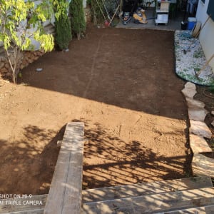 חצר עם אדמה חשופה, אבנים וכלי גינון