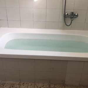 אמבטיה לבנה עם מים, אריחים לבנים על הקיר