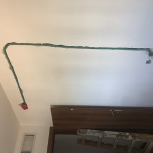 חוטי חשמל ירוקים על קיר לבן עם קופסה אדומה