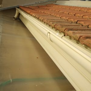 רעפים חומים על גג עם מרזב לבן