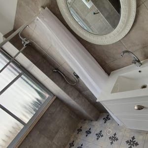 מקלחת עם וילון לבן, כיור ומראה עגולה