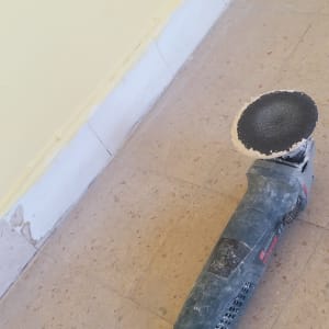 מלטשת חשמלית על רצפה ליד קיר צבוע