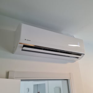 מזגן קיר לבן מותקן מעל דלת