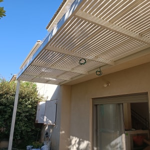 פרגולה לבנה עם צמחייה מסביב