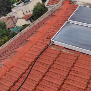 גג רעפים אדום עם פאנלים סולאריים וכבלים