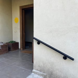 מעקה שחור על קיר חיצוני ליד דלת כניסה