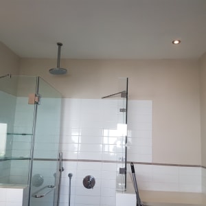 קיר צבוע בצבע בהיר ליד מקלחת זכוכית