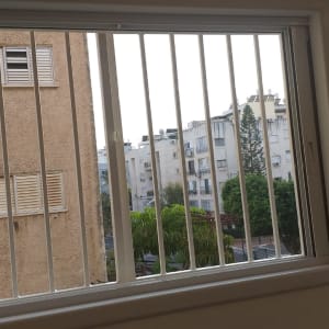 חלון עם סורגים לבנים מול בניין מגורים