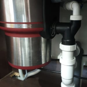 מתקן טוחן אשפה מתחת לכיור עם צינורות חיבור
