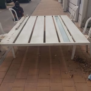 שער חשמלי לבן מונח על מדרכה עם כיסאות פלסטיק