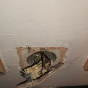 חוטי חשמל חשופים בקיר עם שקע פתוח