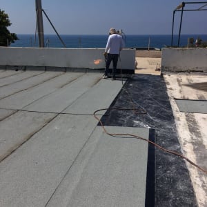 אדם מבצע איטום גג בעזרת מבער גז