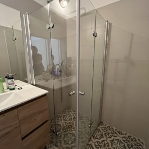 מקלחון זכוכית עם דלתות מתכת בחדר אמבטיה