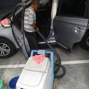 אדם מנקה רכב עם שואב אבק תעשייתי