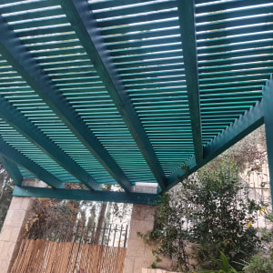 פרגולה מעץ בגינה עם צמחייה מסביב