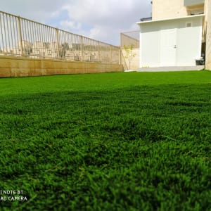 דשא ירוק מלאכותי בחצר מגודרת