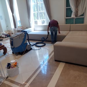 אדם מנקה ספה עם מכונת ניקוי וציוד נוסף
