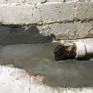 צינור חלוד עם תיקון בטון על קיר ורצפה