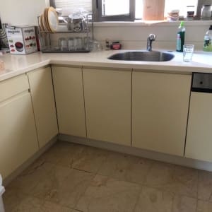 מטבח עם ארונות, כיור וברז, כלים על השיש