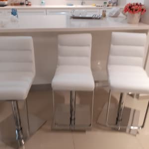 שלושה כיסאות מרופדים בלבן עם בסיס מתכת