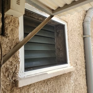חלון אלומיניום עם תריסים בזווית על קיר חיצוני