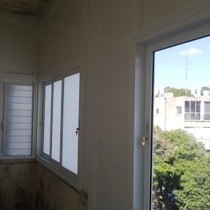 חלונות אלומיניום עם מסגרות לבנות במרפסת סגורה