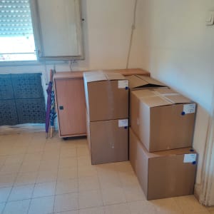 קופסאות קרטון מסודרות ליד ארון עץ קטן