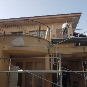 פועלים על פיגומים צובעים קירות חיצוניים של בית