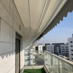 סוכך לבן מותקן על מרפסת עם נוף עירוני