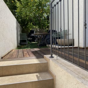 דק עץ עם מעקה מתכת ועציץ גדול