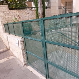 גדר מתכת ירוקה עם סימני צבע לבן