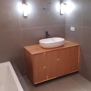 ארון עץ עם כיור לבן וברז בחדר אמבטיה