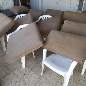 כריות ספה חומות מונחות על כיסאות פלסטיק לבנים