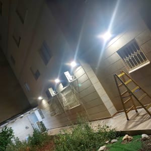 סולם עומד ליד קיר עם תאורה חיצונית