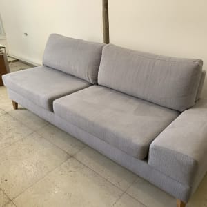 ספה אפורה נקייה עם כריות על רצפה בהירה