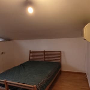 חדר עם קירות צבועים, מנורה חשופה ומזגן מותקן