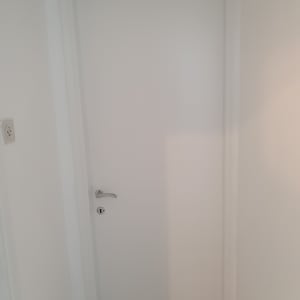 דלת לבנה עם ידית כסופה על רקע קיר לבן