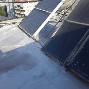 גג אטום עם חומר לבן ליד קולטי שמש