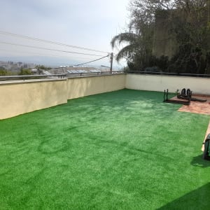 דשא סינתטי עם צינור השקיה מגולגל על גלגלת