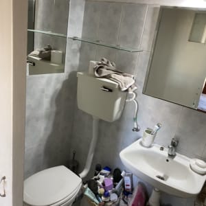 Bathroom with toilet, sink, and renovation tools visible