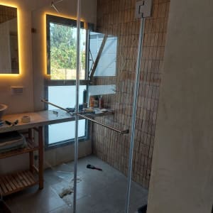 מקלחון זכוכית עם דלת פתוחה ומוצרים על המדף