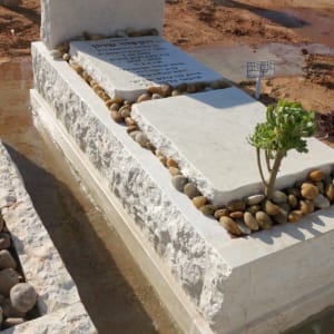 מצבה עם כיתוב בעברית ואבנים קטנות