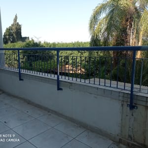 מעקה מתכת כחול על מרפסת מרוצפת