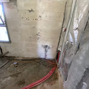 קירות חשופים עם צינורות אדומים ושקע חשמל