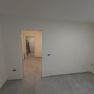 קירות גבס לבנים בחדר ריק עם רצפת אריחים אפורה