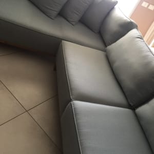 ספה אפורה עם כריות על רצפת אריחים