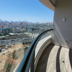 מעקה זכוכית מעוקל במרפסת עם נוף עירוני